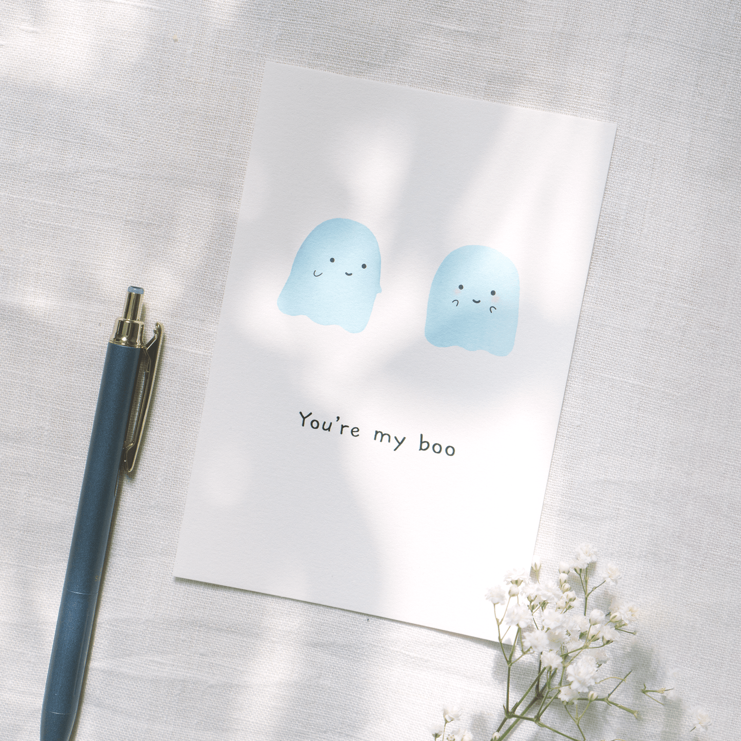 postcard you're my boo with two blue watercolor ghost illustration with writing pen and flowers background 